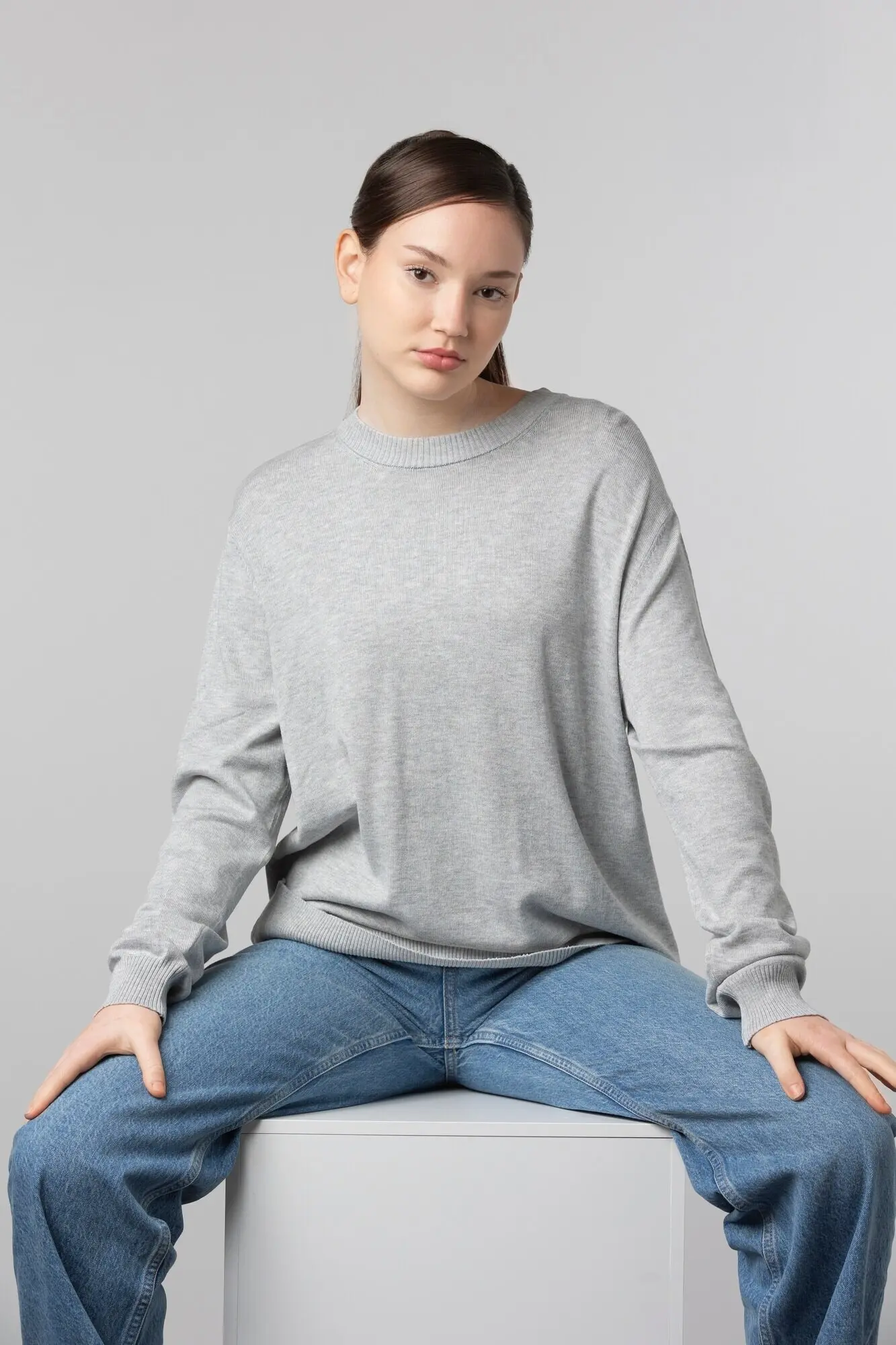 Ein Mädchen trägt ein graues T-Shirt und posiert im Studio.